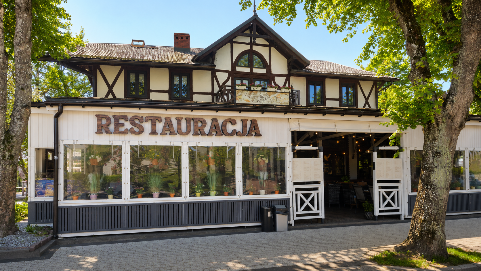 Frontowa fasada Ustronianki ze szyldem Restauracja, przeszklonym tarasem i zielenią